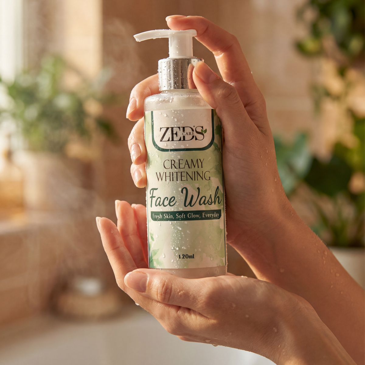 Hand holding a bottle of Zee's Creamy Whitening Face Wash with a blurred bathroom background